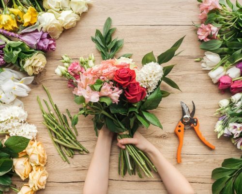 cropped-view-of-florist-holding-flower-bouquet-on-wooden-table.jpg